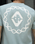 Light blue t-shirt with white geometric pattern on the back, worn by a person.