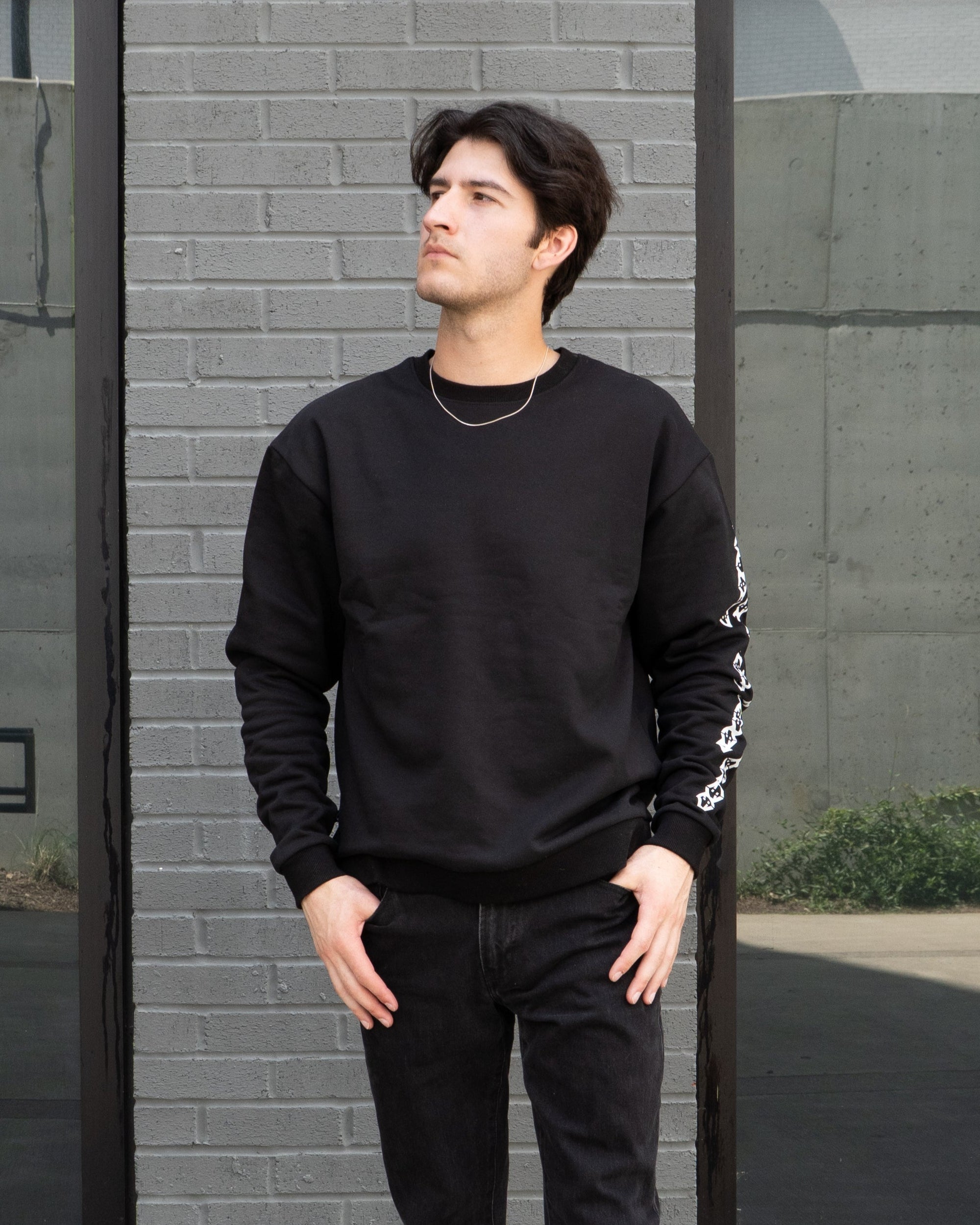 Man wearing a black outfit standing in front of a modern building.